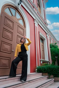 Beautiful asian woman (LGBTQ) natural makeup wear fashion yellow leather clothes with glasses posing at old town and vintage building outdoor fashion style