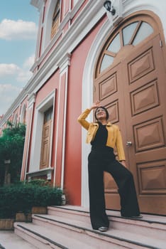 Beautiful asian woman (LGBTQ) natural makeup wear fashion yellow leather clothes with glasses posing at old town and vintage building outdoor fashion style