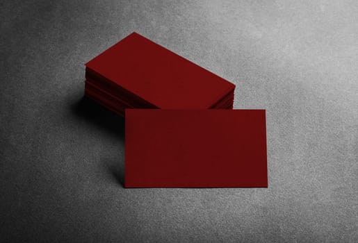 Stack of blank dark red business card on grey textured background top view. Identify design, corporate templates.