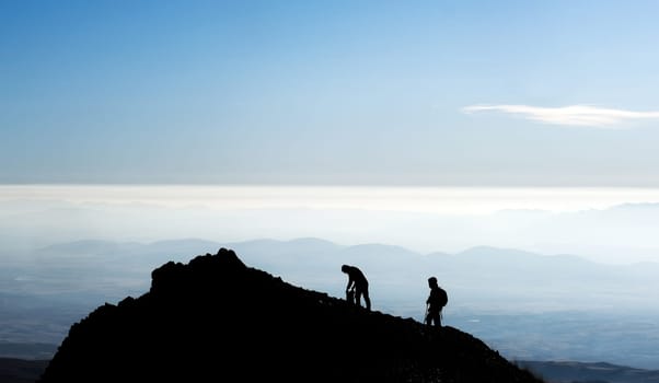 Silhouette of hikers on mountain top on clear sky background