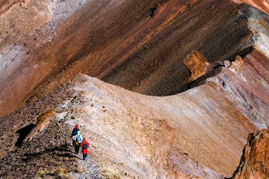 Group of tourists hiking along mountain road on peak