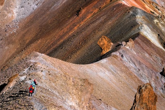 Group of tourists hiking along mountain road on peak