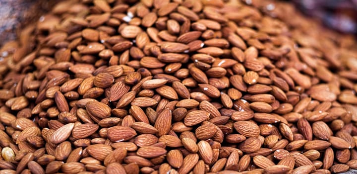 Texture of delicious natural almonds lying in pile, widescreen