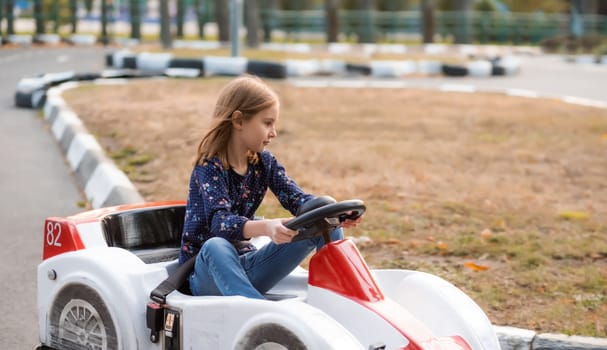 Little girl driving car on kids road in adventure park