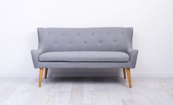 Gray couch standing on light laminate floor near white wall