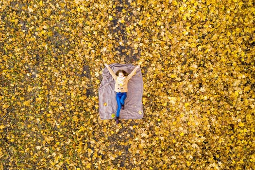 Overviewed school girl lying on carpet of leaves