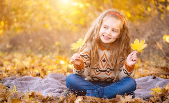 Cute little girl holding yellow leaves outdoors