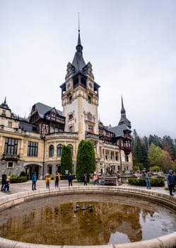 Sinaia, Romania - 30 November 2019: Tourists near inactive fountain in front of Peles Castle