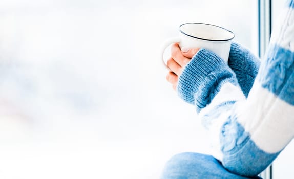 Girl resting with cup of tea sitting near window