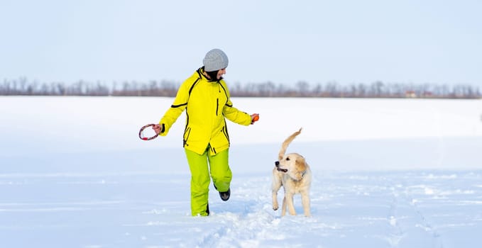Girl with cute young retriever dog on winter walk