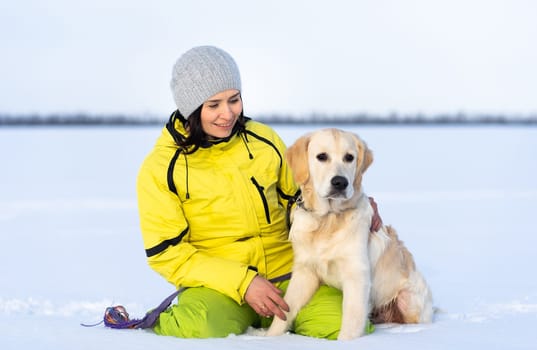 Beautiful girl with lovely young retriever dog outside in winter