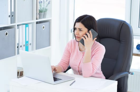 Beautiful business woman working using phone and laptop
