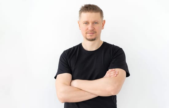 Handsome man in black t-shirt with hands crossed isolated on white background