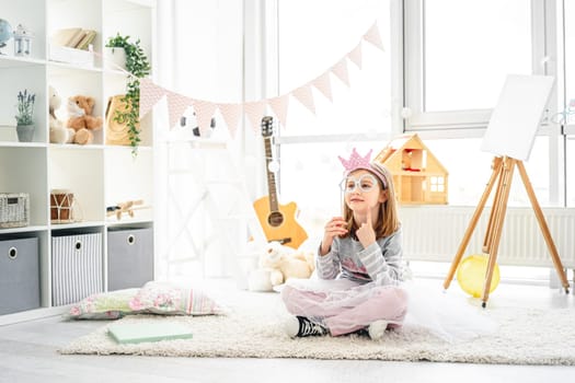 Pretty little girl playing with paper glasses in bright room