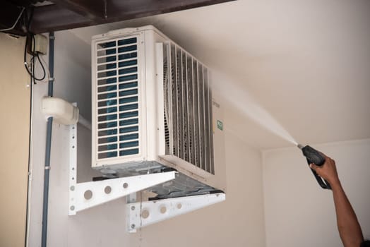 Bangkok, Thailand - July 22, 2017 : Unidentified worker to cleaning coil cooler of air conditioner by water for clean a dust on the wall in customer home when maintenance service