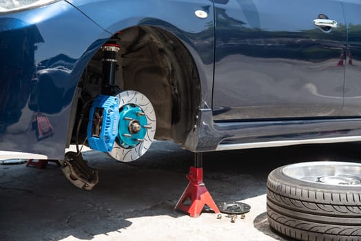 Bangkok, Thailand - March 6, 2021 : Unidentified car mechanic or serviceman disassembly and checking a disc brake and asbestos brake pads for fix and repair problem at car garage or repair shop