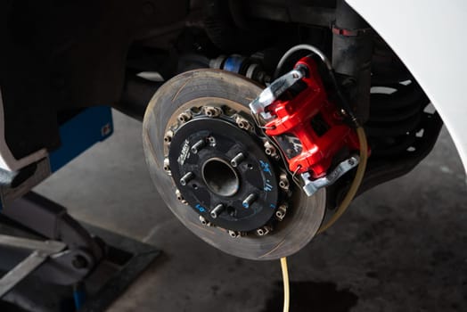 Bangkok, Thailand - February 4, 2023 : Unidentified car mechanic or serviceman disassembly and checking a disc brake and asbestos brake pads for fix and repair problem at car garage or repair shop