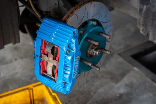 Bangkok, Thailand - February 4, 2023 : Unidentified car mechanic or serviceman disassembly and checking a disc brake and asbestos brake pads for fix and repair problem at car garage or repair shop