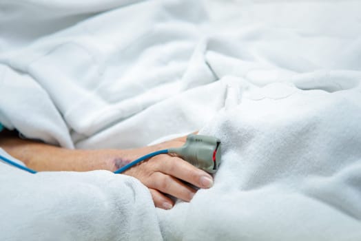 Patient asian elder woman 80s flu covid19 with pulse gauge for heartbeat measuring and blood pressure on a patient elderly finger on patient bed in intensive care unit (ICU.) room at hospital