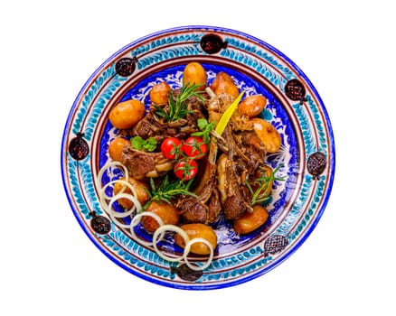 A top view of a national Uzbek dish with meat and potatoes served in a plate with traditional patterns