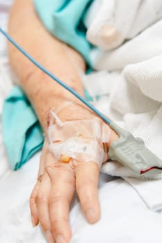 Patient asian elder woman 80s flu covid19 with pulse gauge for heartbeat measuring and blood pressure on a patient elderly finger on patient bed in intensive care unit (ICU.) room at hospital