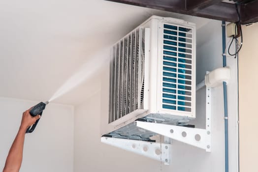 Worker to cleaning coil cooler of air conditioner by water for clean a dust on the wall in customer home when maintenance service