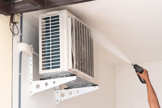 Worker to cleaning coil cooler of air conditioner by water for clean a dust on the wall in customer home when maintenance service