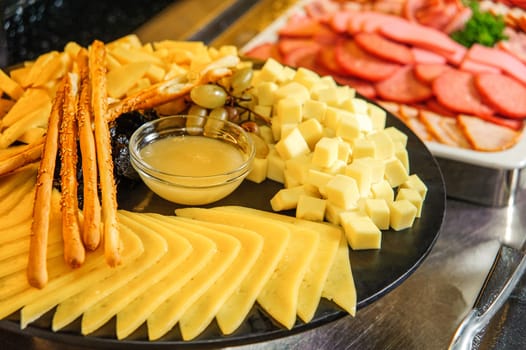 A plate of cheese set with honey on a buffet table