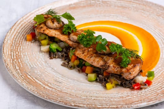 A closeup shot of a Fish course with salmon meat, herbs and orange sauce on a marble plate