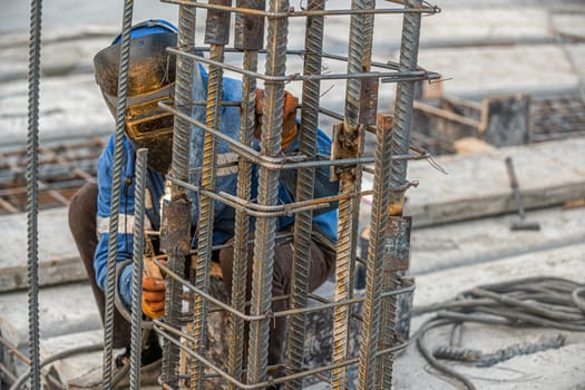 A welder on the construction site makes a metal structure for pouring concrete