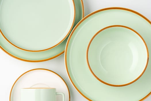 A set of white and pastel green ceramic tableware with orange outlines. Top view