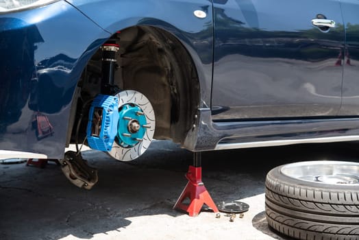 Car mechanic or serviceman disassembly and checking a disc brake and asbestos brake pads for fix and repair problem at car garage or repair shop