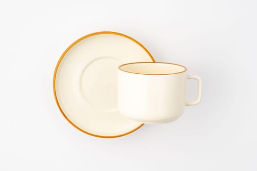 A set of white and brown ceramic plate and cup on a white background. Top view