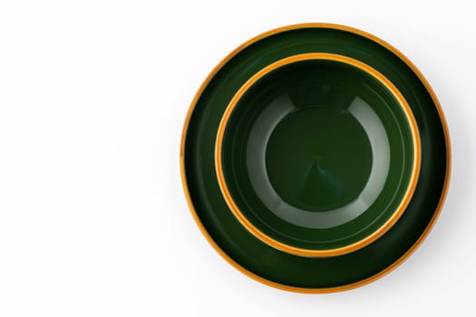 A set of dark green ceramic tableware with orange outlines on a white background