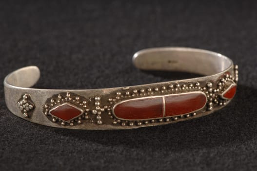 An antique, elegant bracelet with engraving and precious red stones isolated on a black background