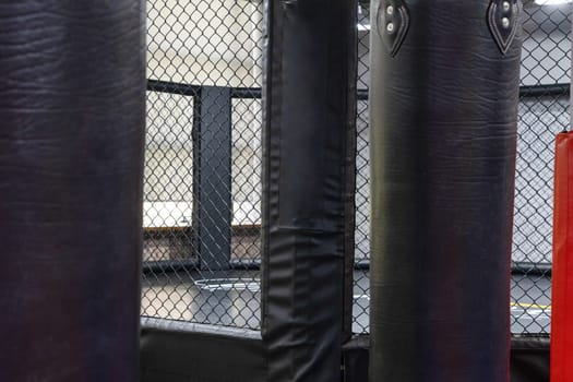 An octagonal kickboxing cage with boxing bags in the sports complex