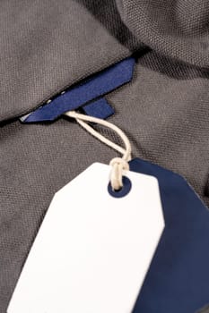 A vertical closeup shot of white blue tags on a string on a cloth with a blank blue tag on the neck