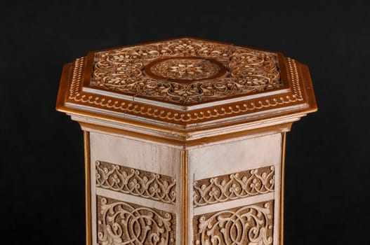 The antique oriental wooden table with the artistic carving on a black background, Uzbekistan, close-up