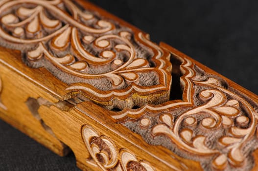 A close-up artistic wood carving on the pencil case on a black background. Central Asia, Uzbekistan