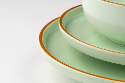 A set of pastel green ceramic tableware with orange outlines. Close-up