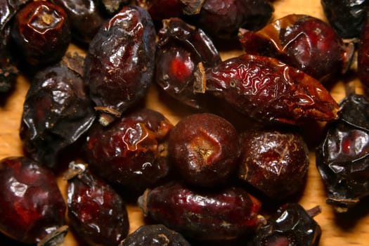 Dried rosehip berries on kitchen board, extreme close-up, macro view