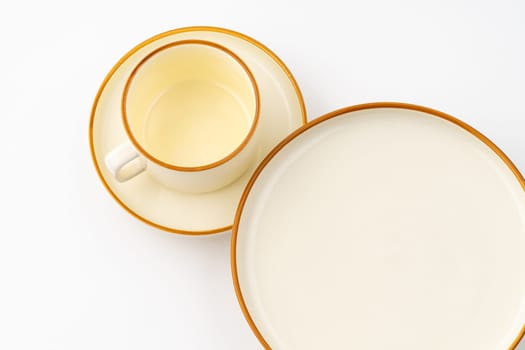 A set of white and brown ceramic plate and cup on a white background