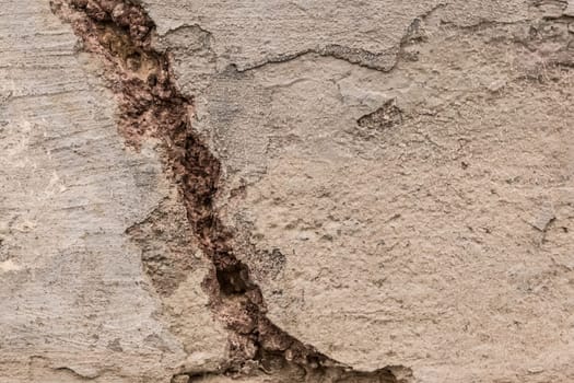 A crack in the old concrete is a close-up. Broken cement worn texture damage background.