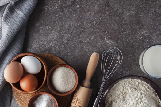 Preparation for baking. Eggs, sugar, milk, flour, salt, rolling pin, whisk on the kitchen table. copy space
