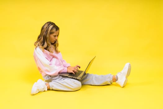 Little blonde kid girl on a pastel yellow wall background. Childhood lifestyle concept.