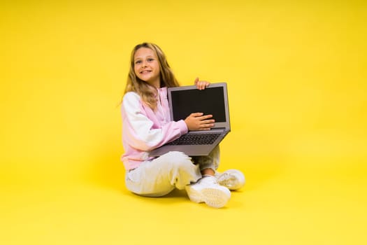 Little blonde kid girl on a pastel yellow wall background. Childhood lifestyle concept.