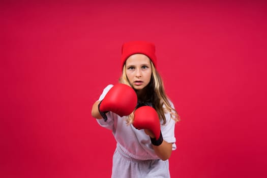 Cute little girl in boxing gloves on a red background studio