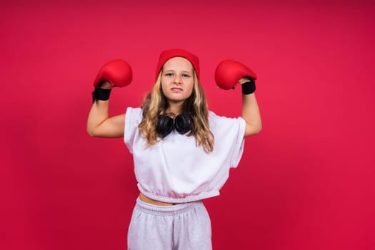 Cute little girl in boxing gloves on a red background studio