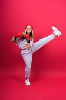 Cute little girl in boxing gloves on a red background studio