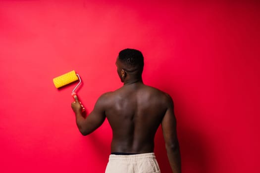 African-American painter on a red studio background topless